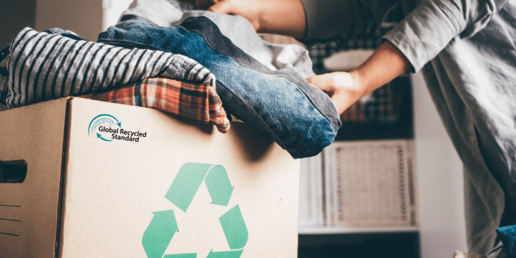 Quelqu'un qui se sert dans un carton d'habits recyclés