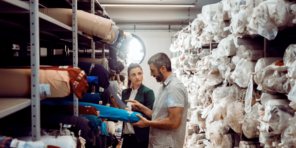 Deux personnes qui observent un rouleau de tissu dans une usine textile