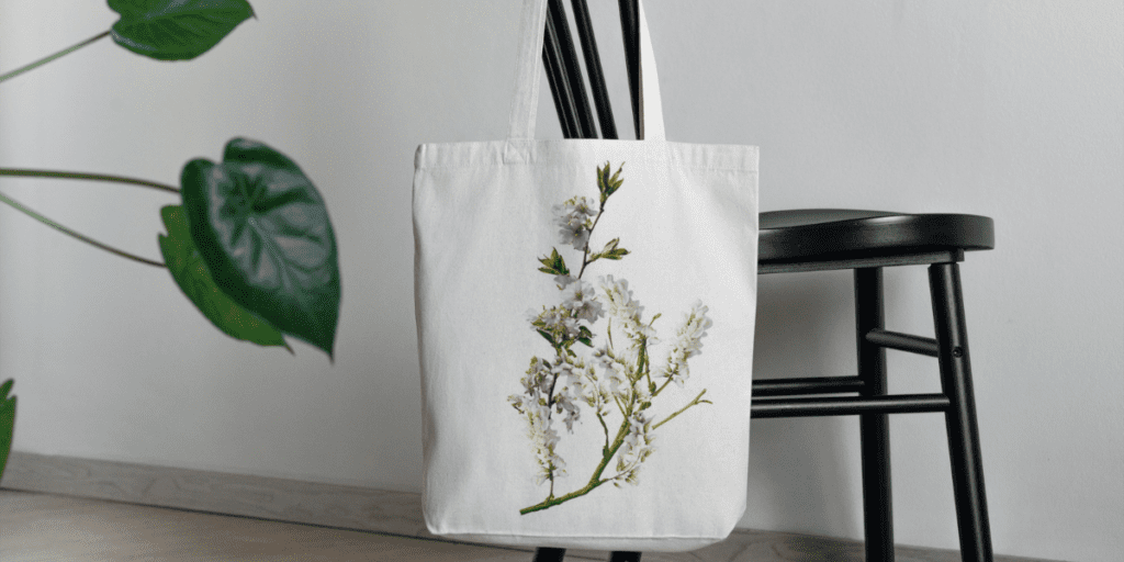 Tote-bag coton personnalisé avec une fleur accroché sur une chaise